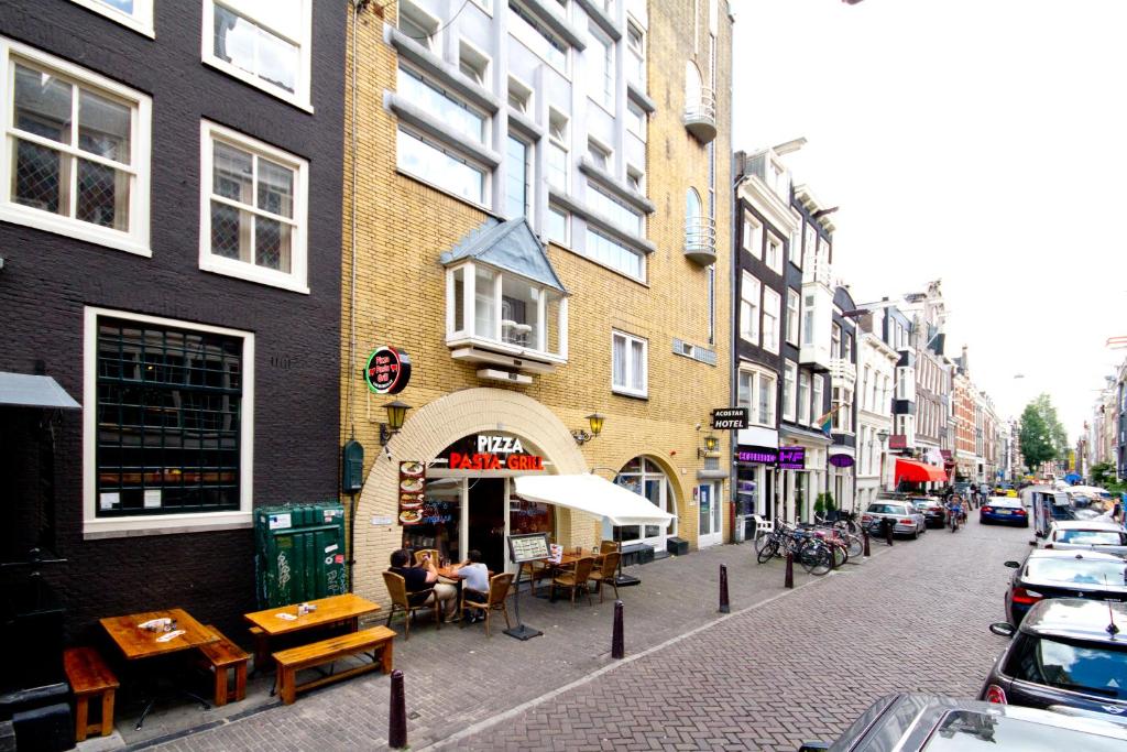 una calle de la ciudad con mesas y sillas y un edificio en Acostar Hotel, en Ámsterdam