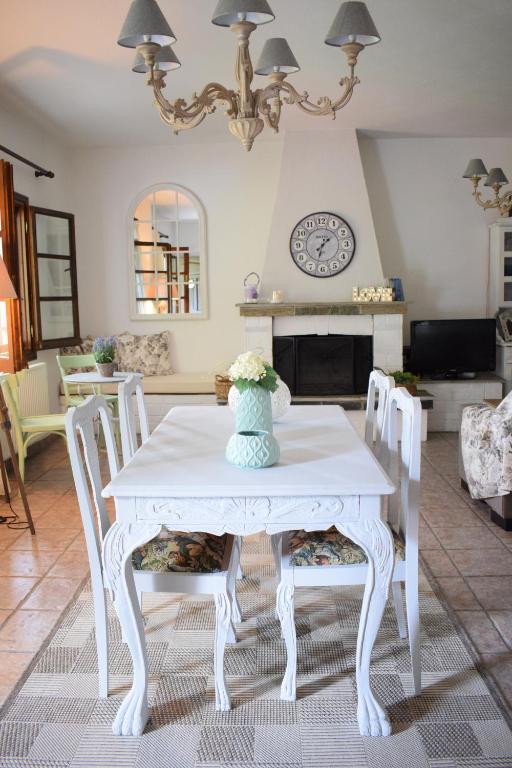 una mesa blanca con sillas y un jarrón de flores. en Aspasia's Villa, en Prinos