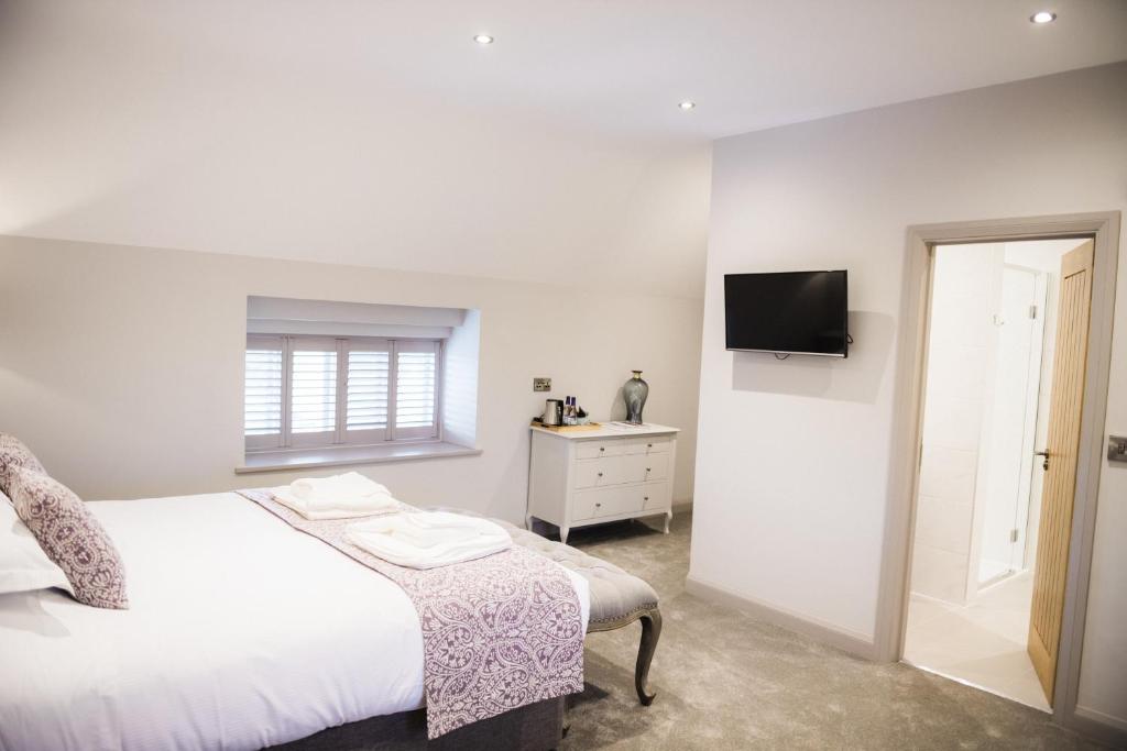 a bedroom with a bed and a tv on a wall at Rutland Water Courtyard Rooms in Oakham