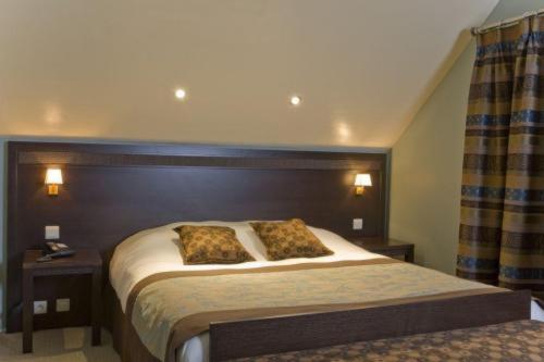 een slaapkamer met een bed met 2 kussens erop bij Hotel Les Mignees in Barvaux