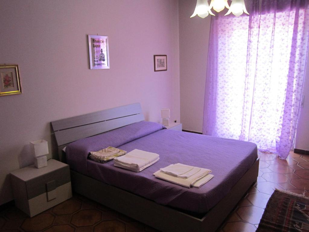 パルティニーコにあるAppartamento Vacanza Lunaのベッドルーム1室(紫色のベッド1台、タオル付)