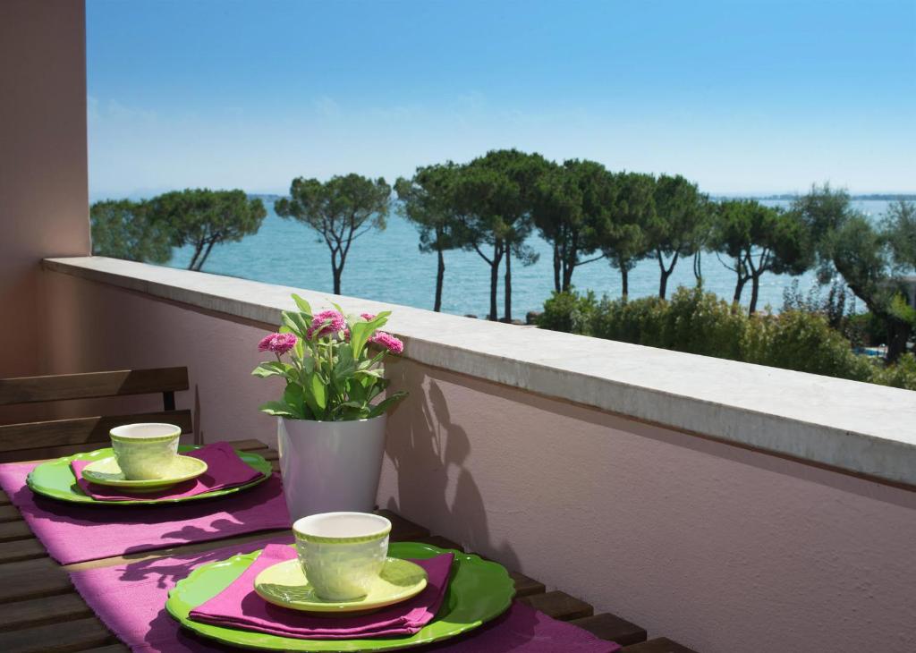 Garda Blue Lake Home Luxury Appartment في ديسينسانو ديل غاردا: طاولة مع كوبين وصحون على شرفة