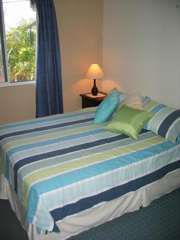 a bed with blue and green pillows and a window at Harriet Place apartment in Darwin