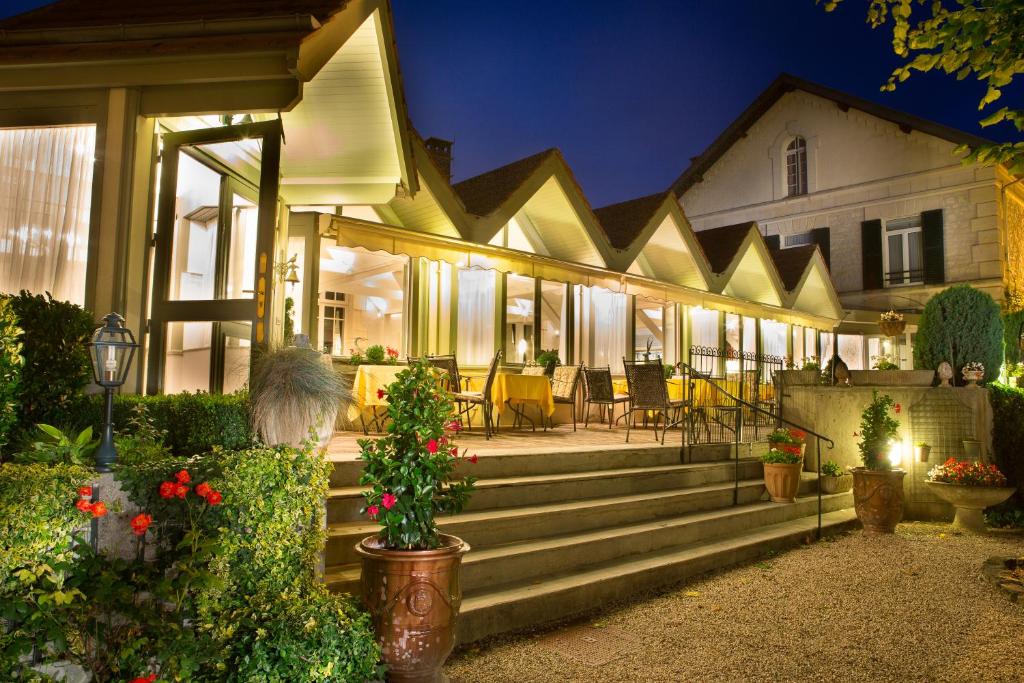 une maison avec une terrasse couverte dotée d'escaliers et de chaises dans l'établissement Hôtel & Restaurant Le Relais d'Aumale, à Orry-la-Ville