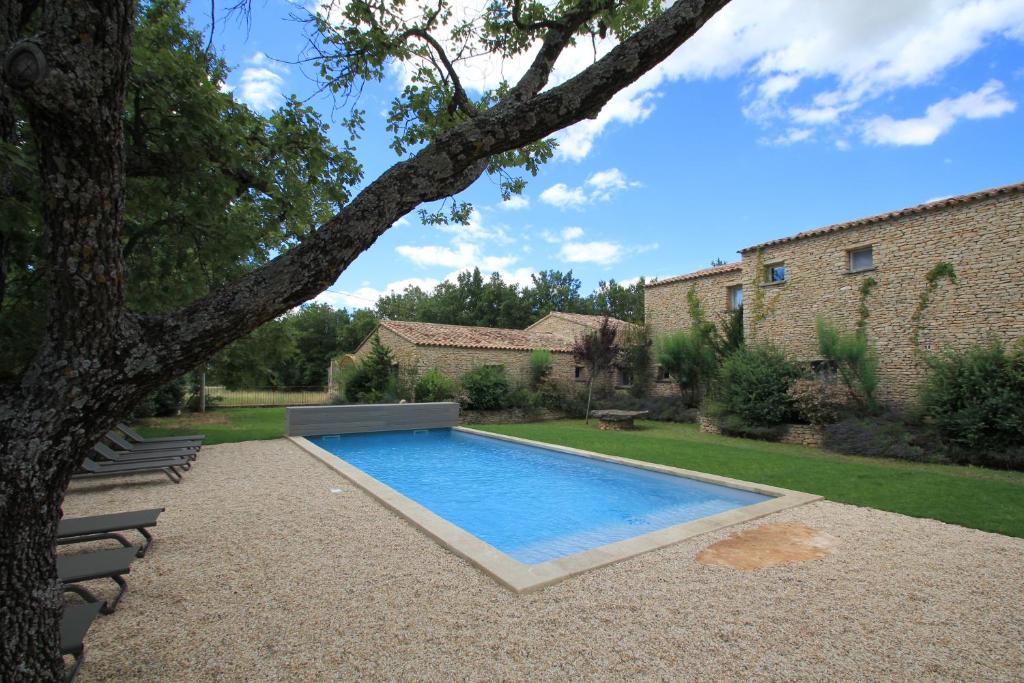 a swimming pool in a yard with a tree at La Caprine in Gordes