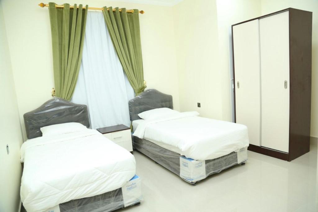 two beds in a room with a mirror at Golden Season Furnished Apartments 5 in Salalah