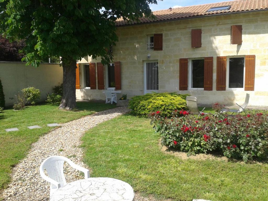 un patio con dos sillas blancas frente a una casa en Galot La Chapelle en Gardegan-et-Tourtirac