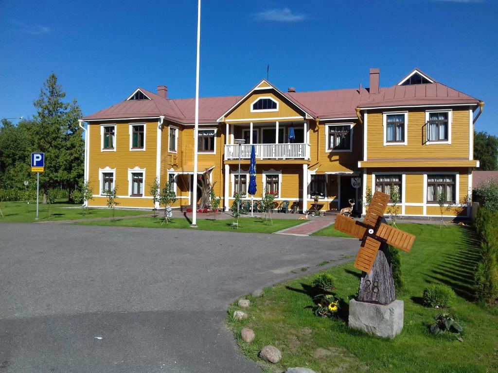 una gran casa amarilla con una cruz delante de ella en Kerihovi, en Kerimäki