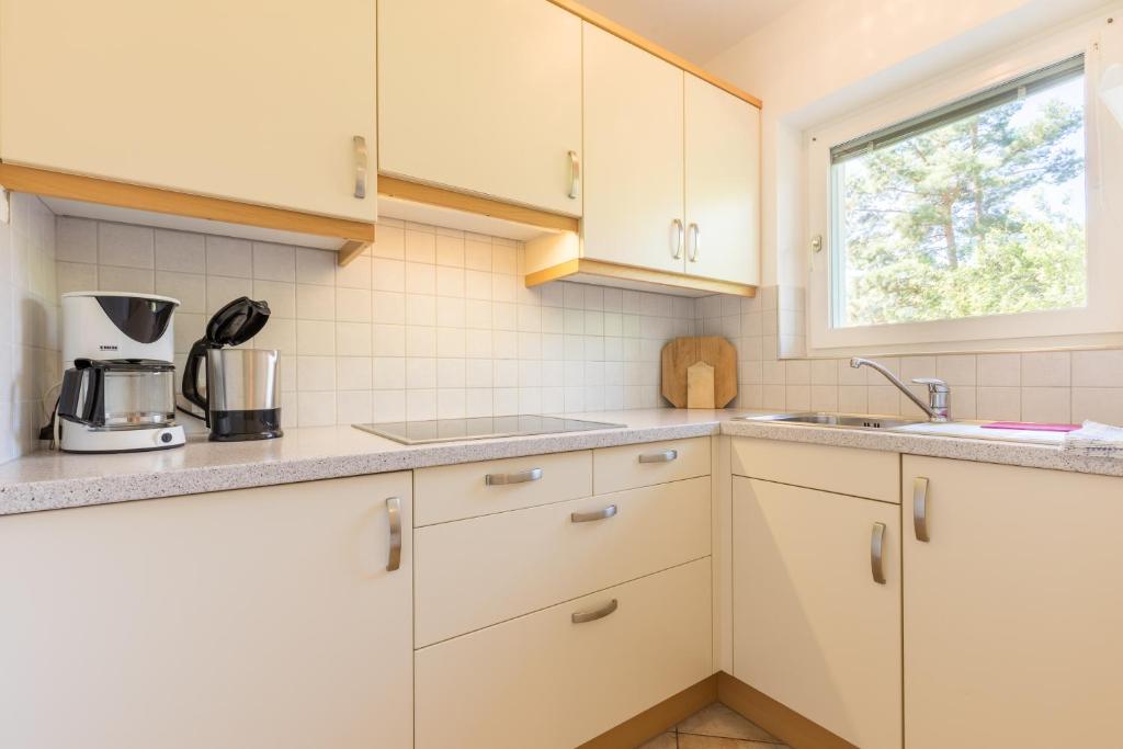 kuchnia z białymi szafkami i oknem w obiekcie Appartements Haus Pichler w mieście Eggen
