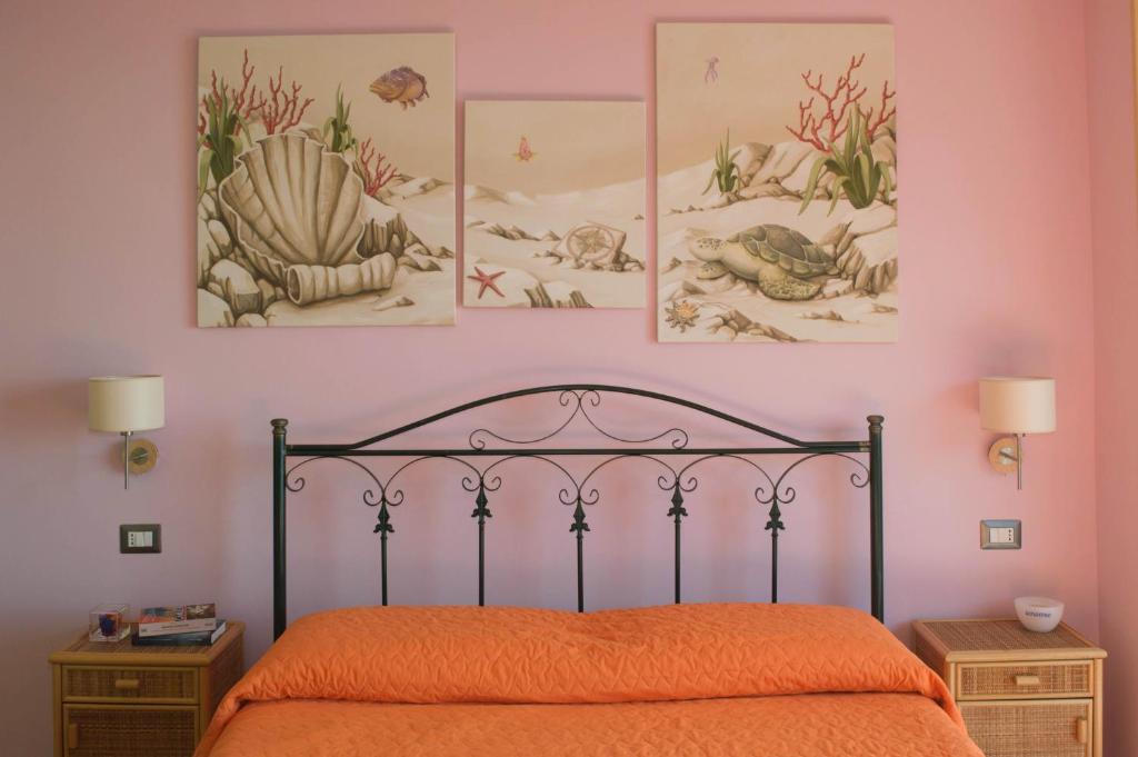 ein Schlafzimmer mit einem Bett mit vier Bildern an der Wand in der Unterkunft B&B Sunshine in Scilla