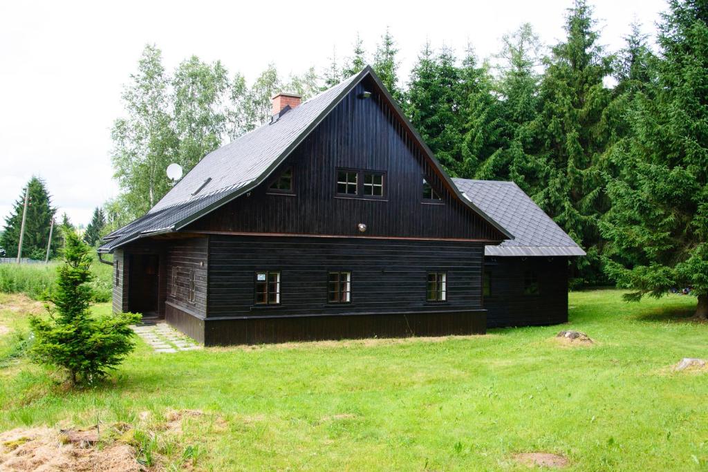 a black barn sitting on top of a green field at Chalupa Na Paloučku in Orlické Záhoří 