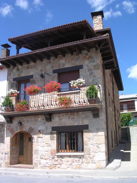 a stone building with potted plants on the balconies at Casa Rural el Sastre in Navaleno