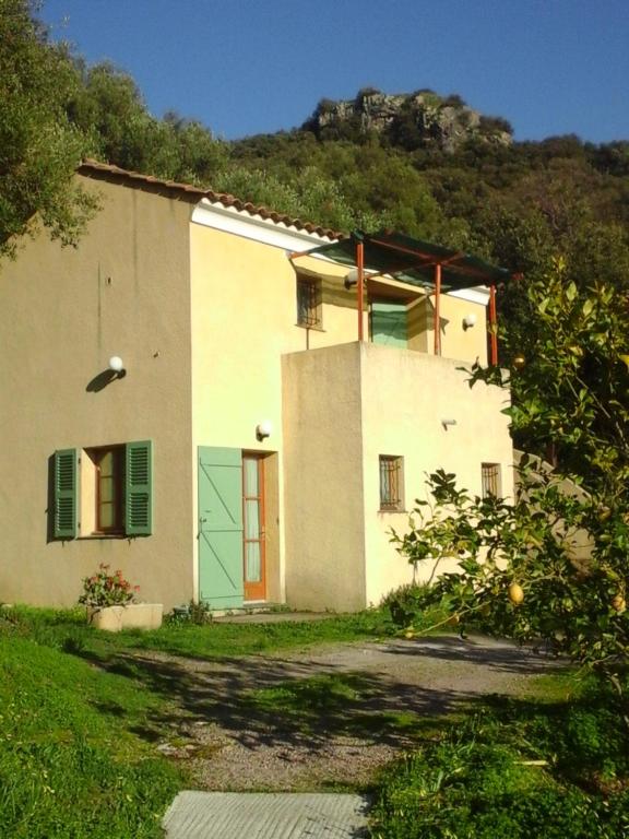 a white house with a green door and a mountain at A CASA DI L'ALIVU in Patrimonio