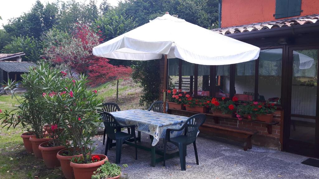 una mesa y sillas bajo una sombrilla en un jardín en La Casina Idro, en Crone