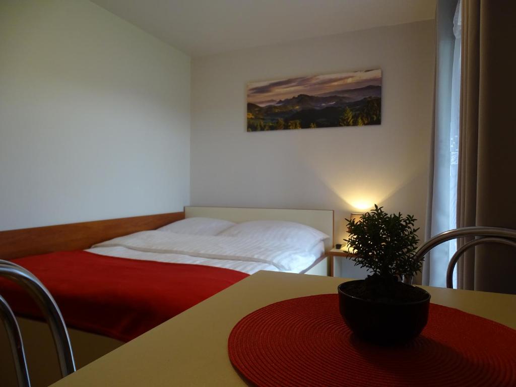 ein Schlafzimmer mit einem Bett und einem Tisch mit einer Topfpflanze in der Unterkunft Pokoje Gościnne A.T. Mikołajczyk in Krościenko nad Dunajcem