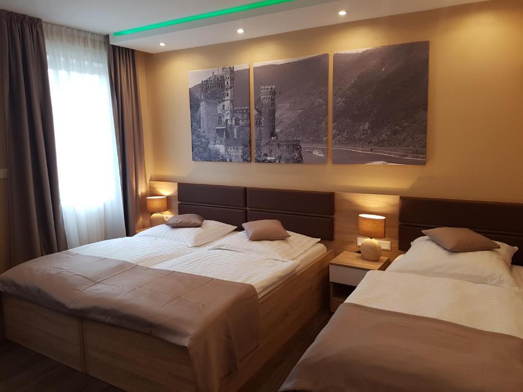 2 Betten in einem Schlafzimmer mit 2 Lampen und einem Fenster in der Unterkunft Hotel Haus Büderich in Meerbusch