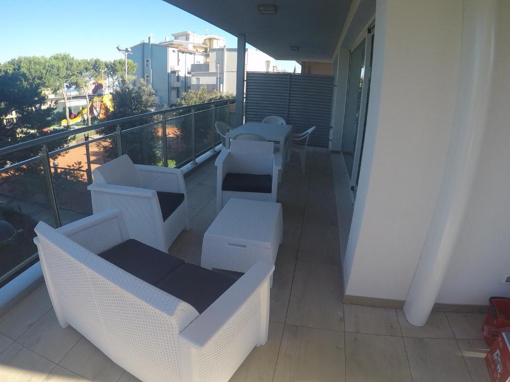 ein Balkon mit weißen Stühlen und Tischen an einem Gebäude in der Unterkunft Mare Incanto - Agenzia Cocal in Caorle