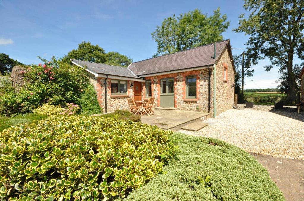 a brick cottage with a patio and a yard at Sheldon Barn in Bideford