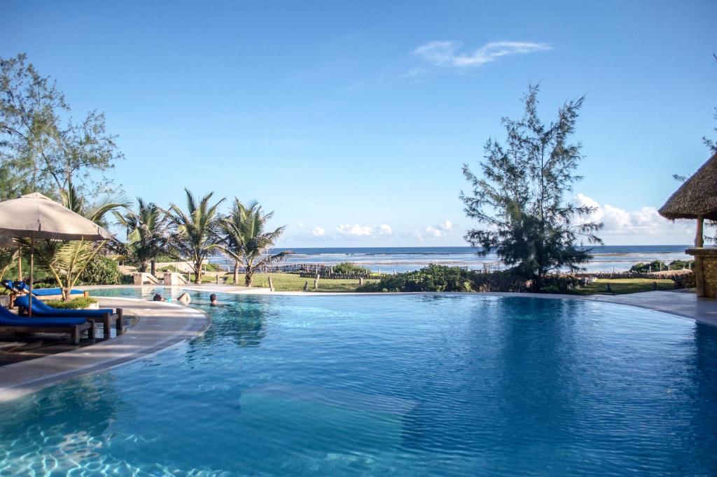 a swimming pool with the ocean in the background at The Charming Lonno Lodge Watamu in Watamu