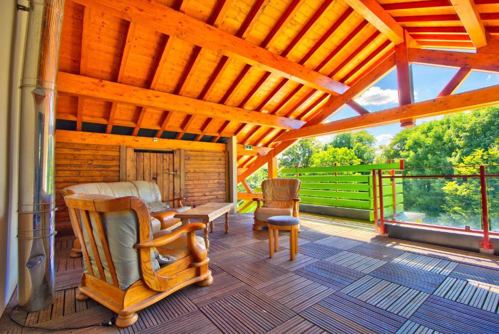 - une terrasse couverte avec un lit, un bureau et des chaises dans l'établissement Logis Hôtel Restaurant Le Chalet du Mont Roland, à Dole