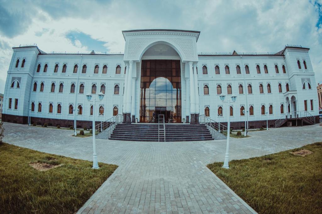 Un grand bâtiment blanc avec un escalier se trouve devant. dans l'établissement Hotel Bek Samarkand, à Samarcande