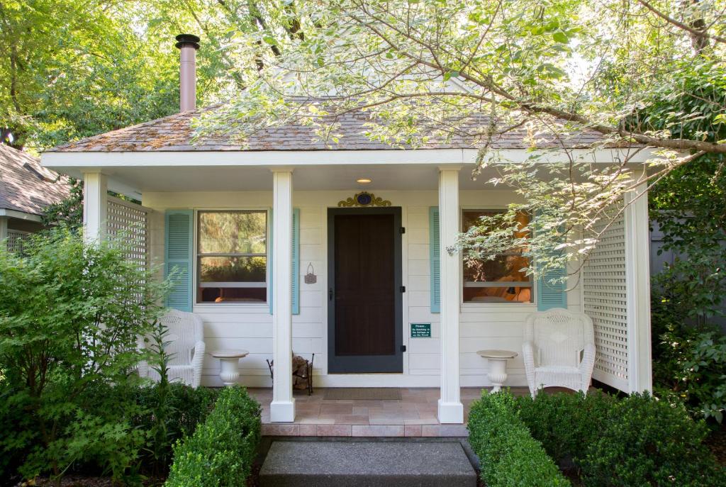 a white house with two chairs and a door at Cottage Grove Inn in Calistoga