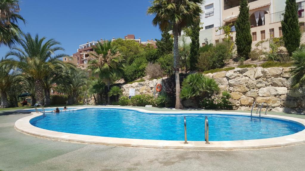 ein großer Pool mit Palmen und Gebäuden in der Unterkunft Cala Golf in Mutxamel