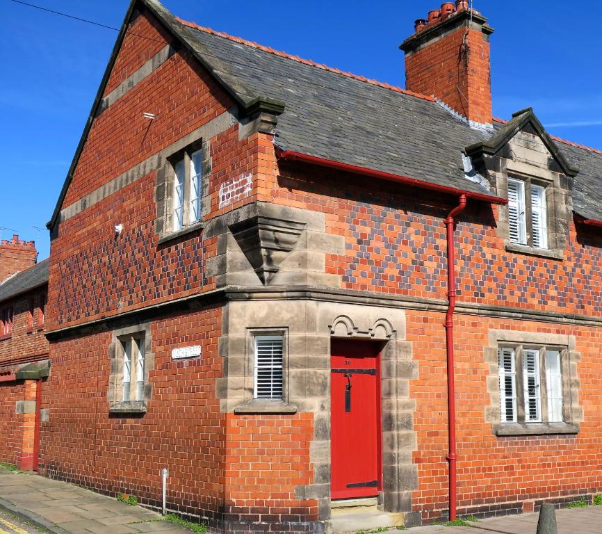 un antiguo edificio de ladrillo rojo con una puerta roja en 30 Overleigh Road en Chester