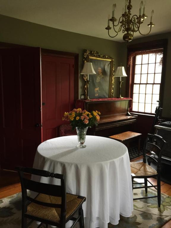 Innkeeper's Place B&B في Stafford Springs: غرفة مع طاولة مع إناء من الزهور عليها