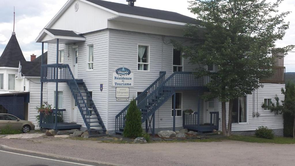 une maison blanche avec un escalier en face de celle-ci dans l'établissement Les Appartements de La Bergeronnette, à Grandes-Bergeronnes