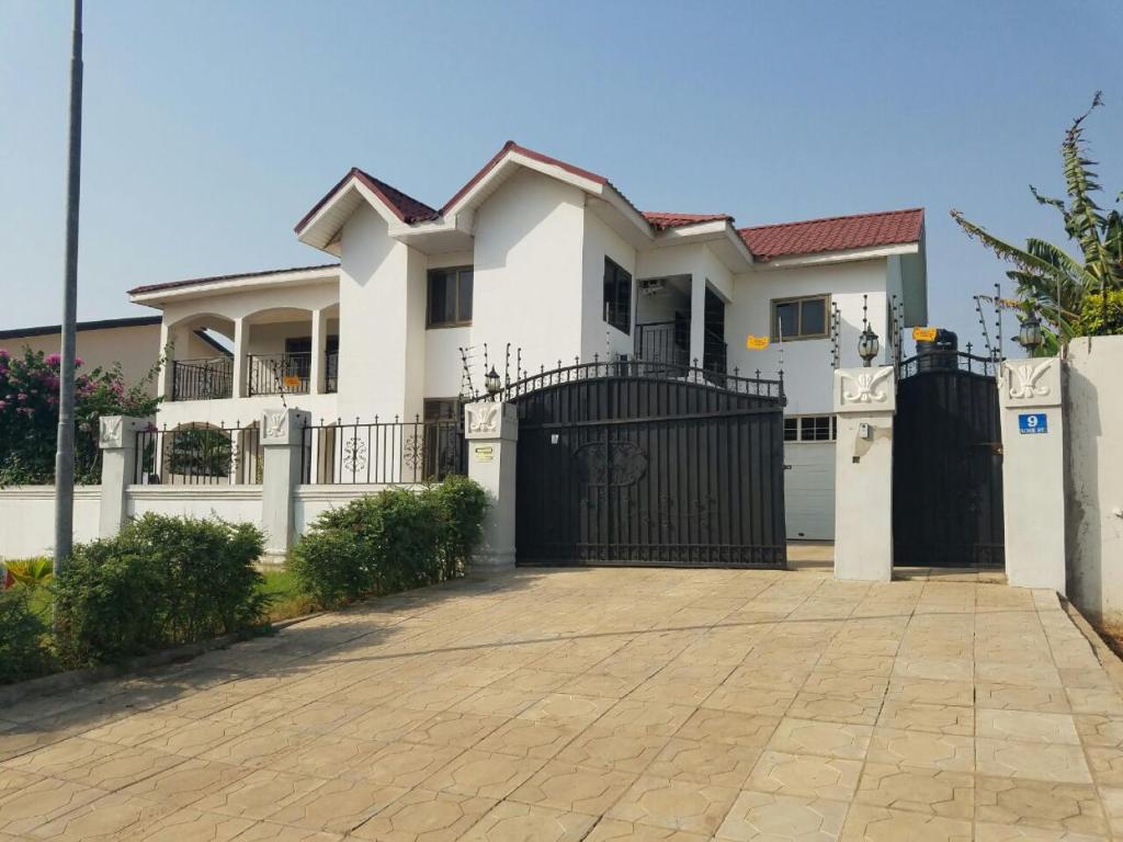 a white house with a black gate and a driveway at Rose Villa in Spintex