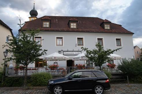 une voiture noire garée devant un bâtiment blanc dans l'établissement Gaststätte Liebl, à Wiesent
