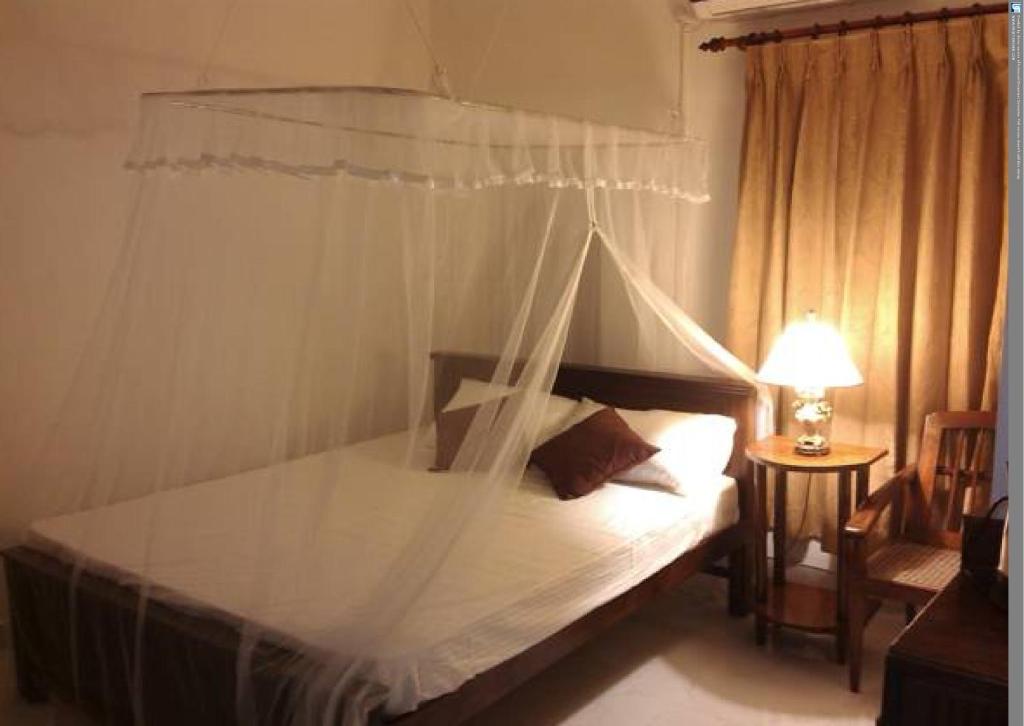a bedroom with a bed with a mosquito net at Number 01 by Taprobane in Negombo