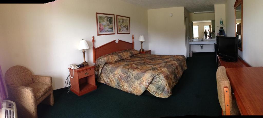 a hotel room with a large bed and a chair at Homegate Inn in Louisville