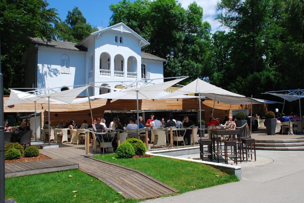 a group of people sitting at tables under umbrellas at Penzion Vila Prešeren in Bled