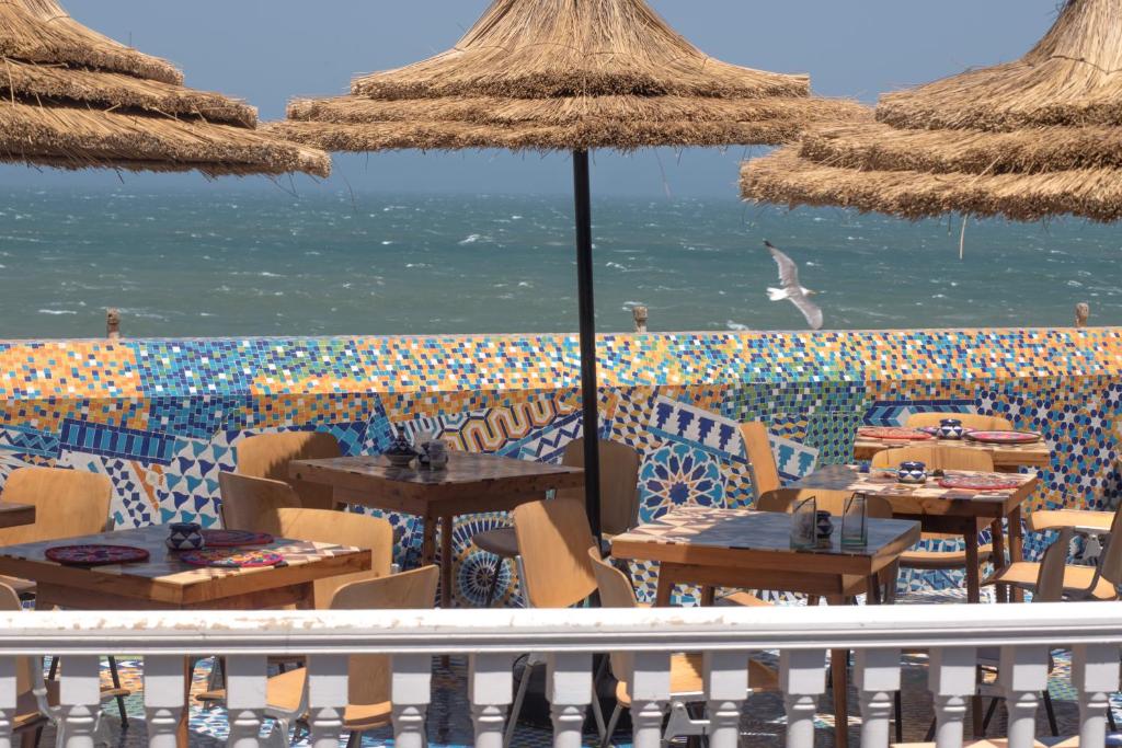 索維拉的住宿－Salut Maroc!，海滩上设有桌子和遮阳伞的餐厅