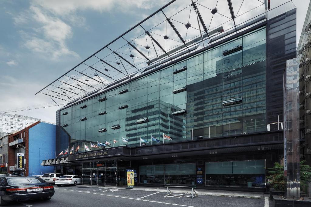 a large glass building with cars parked in front of it at Benikea Daelim Hotel in Daejeon