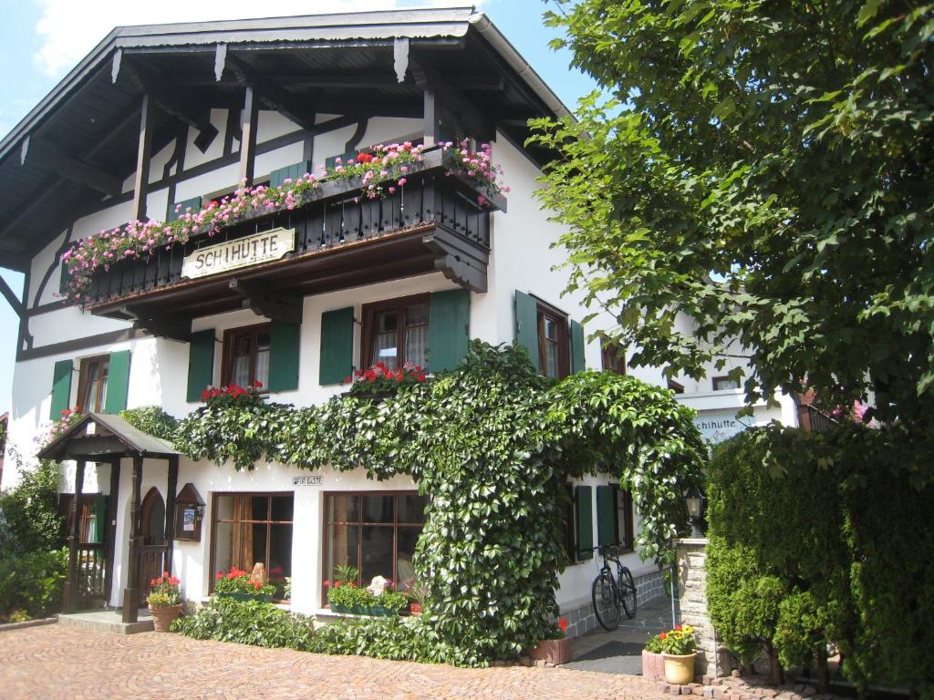 a white building with a balcony with flowers on it at Pension Schihütte in Oberstaufen