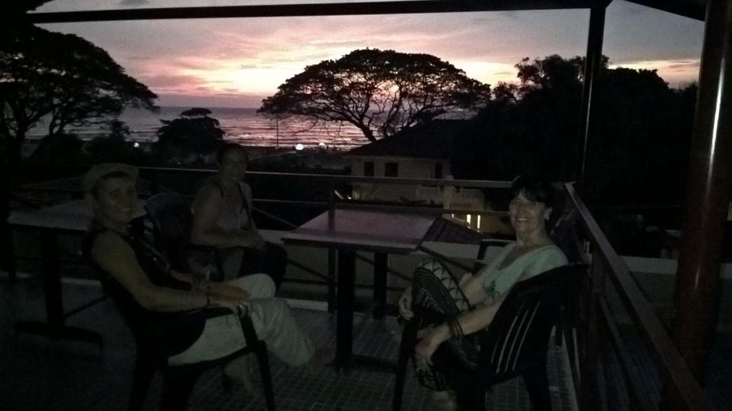 3 personnes assises sur un balcon pour admirer le coucher du soleil dans l'établissement Fortkochi Beach Inn, à Cochin