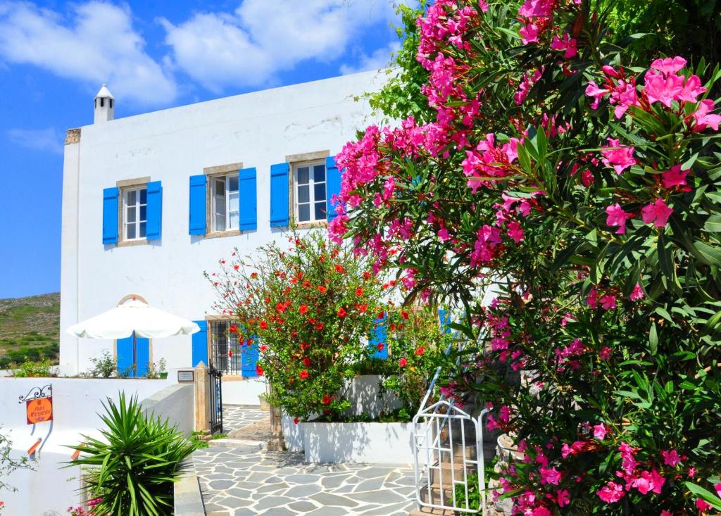 a white building with blue windows and pink flowers at Margarita Hotel in Kythira