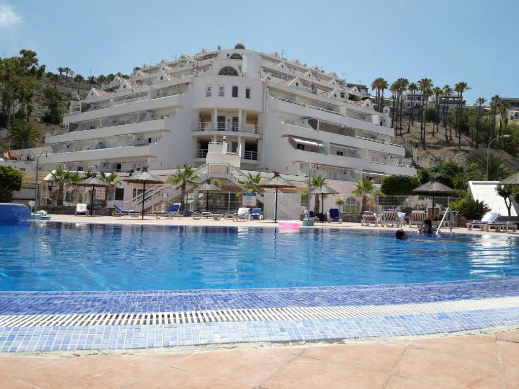 a hotel with a swimming pool in front of a building at COLINA BLANCA TENERIFE. in Adeje