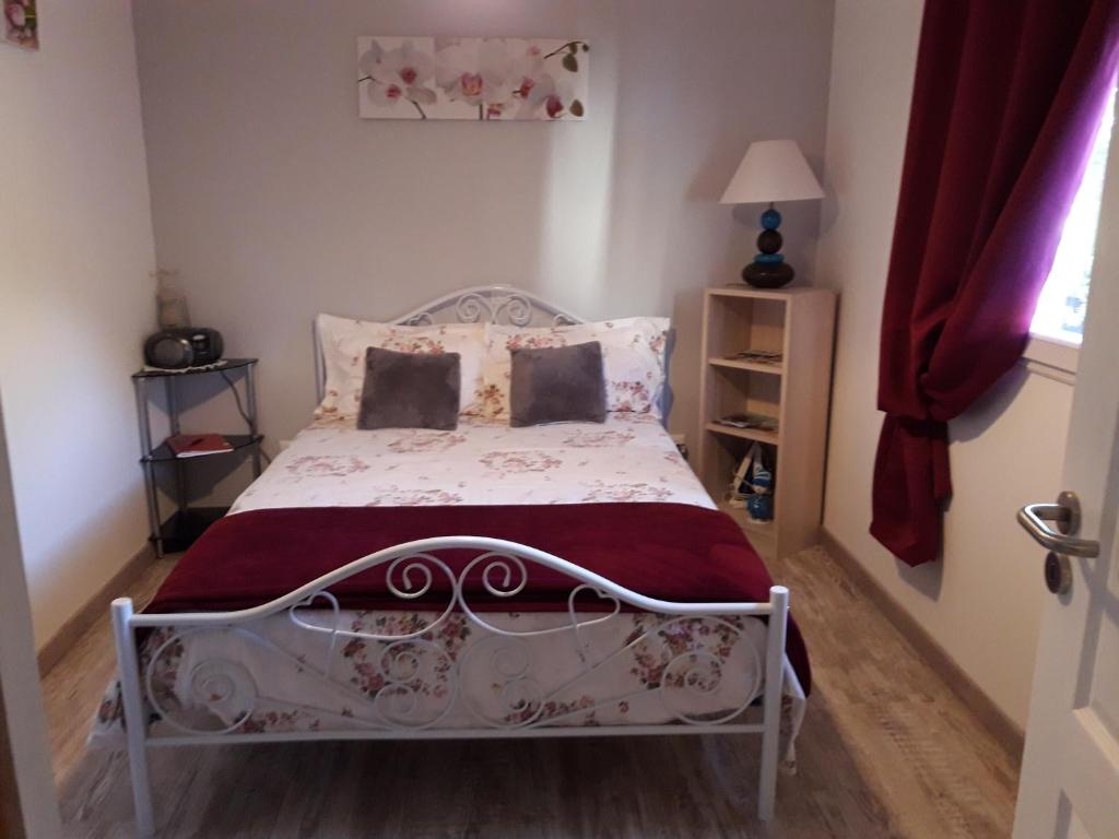 a bedroom with a white bed with a red curtain at Studio à Campagnac in Campagnac