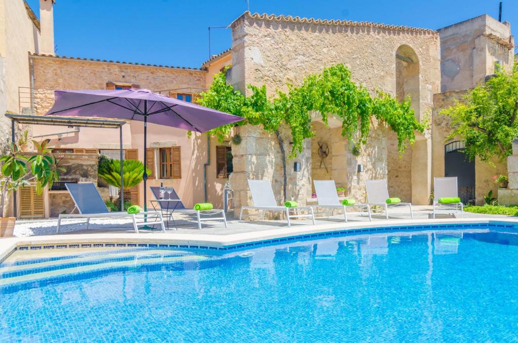 een zwembad met stoelen en een parasol bij Sa Casa Vella in Vilafranca de Bonany