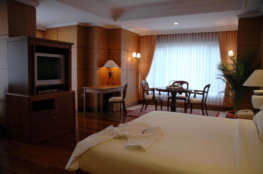 Habitación de hotel con cama, mesa y TV en Royal Senyiur Hotel, en Prigen