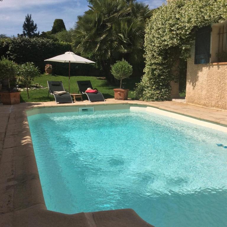 une piscine avec deux chaises et un parasol dans l'établissement Carpédiem, à Sanary-sur-Mer