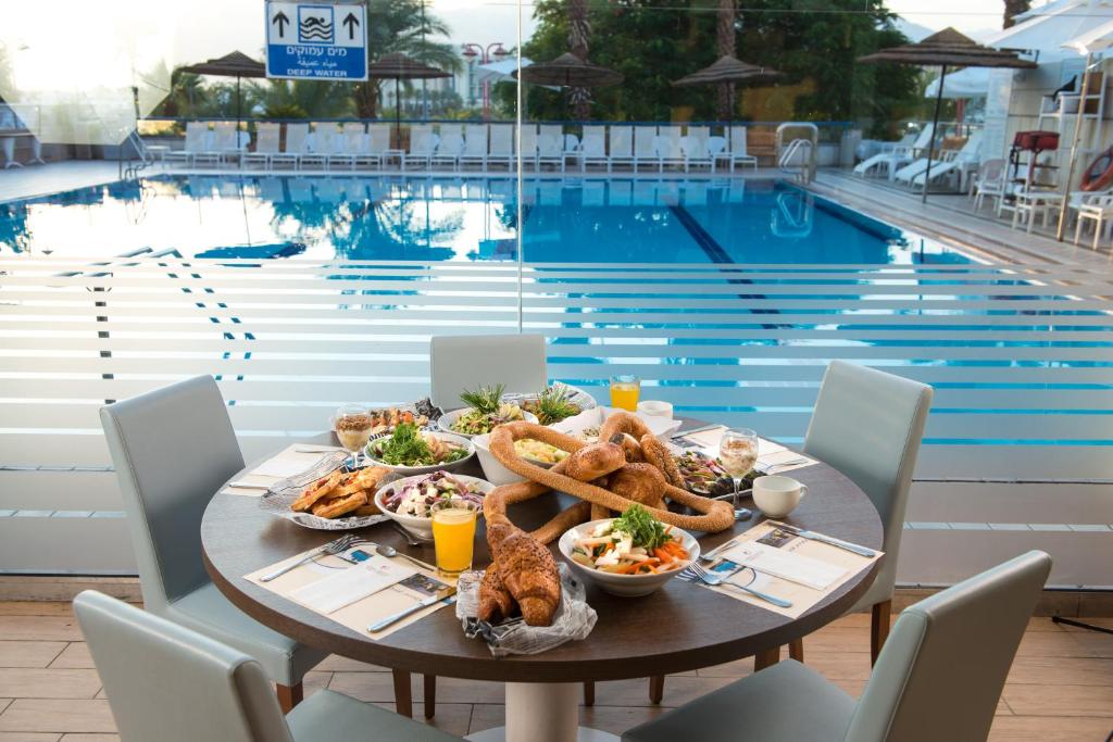 - une table avec de la nourriture à côté de la piscine dans l'établissement Hotel Astral Nirvana Club- Half Board, à Eilat