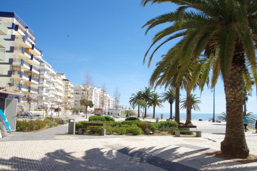 a beach with palm trees and buildings and the ocean at Summer Home in Armação de Pêra