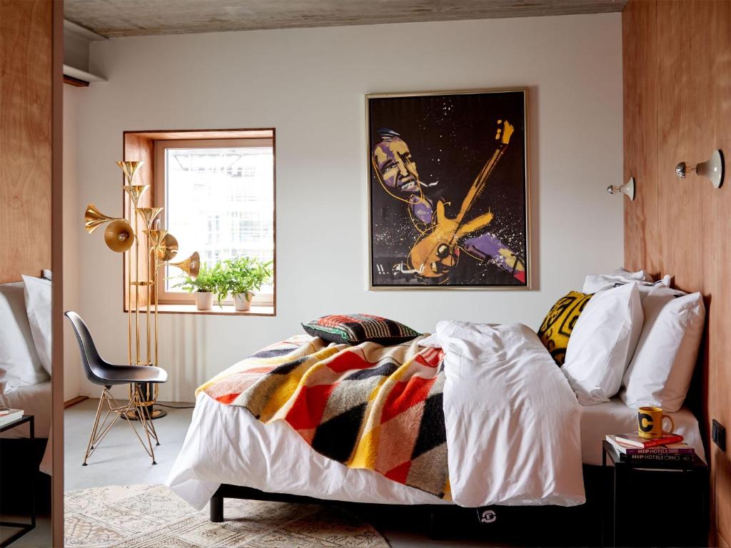 1 dormitorio con 1 cama con una guitarra en la pared en Q-Factory Hotel, en Ámsterdam