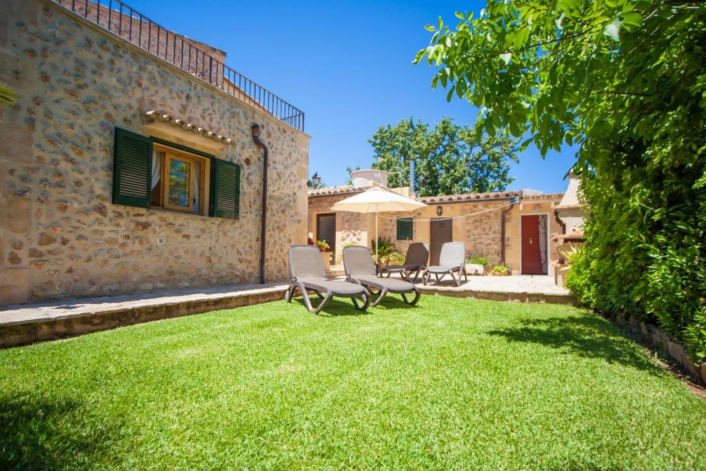 a yard with chairs and an umbrella and a building at Can Boi Den Cifre in Pollença