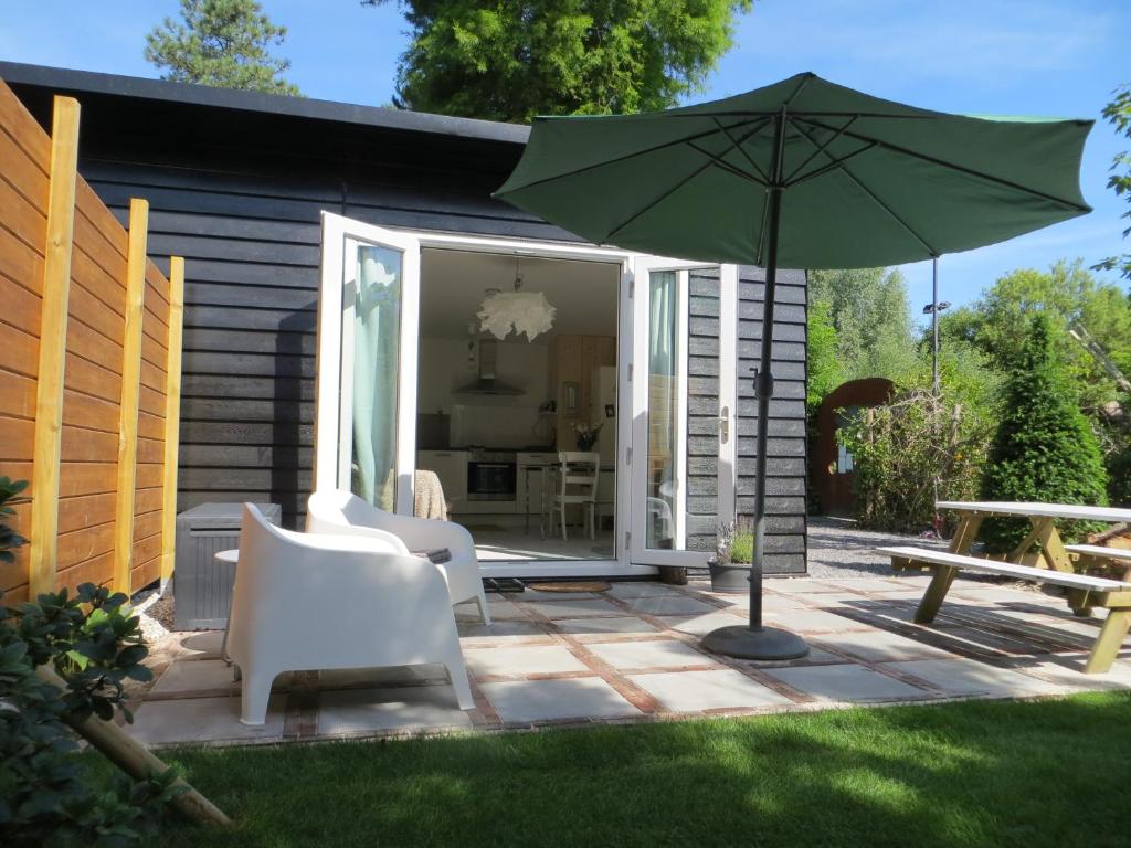 een patio met een parasol, stoelen en een tafel bij Zen in Schoorl in Schoorl